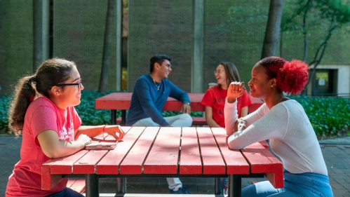 Students laughing and talking at picnic table outside the Rutgers Law School